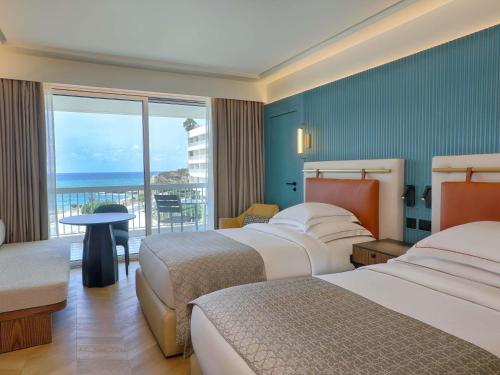 a hotel room with two beds and a view of the ocean at Mövenpick Hotel Beirut in Beirut