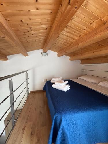 a bedroom with a blue bed in a room with wooden ceilings at Veterani House 33 in Cefalù