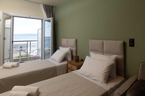 two beds in a room with a balcony at Maistrali Luxury Living in Ouranoupoli