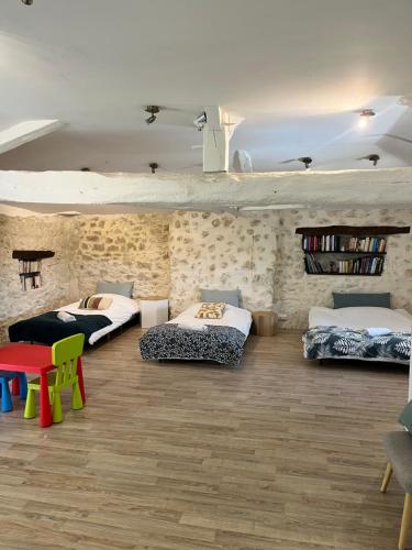 a room with three beds and a table and chairs at Chez Gargatte, gîte 4 chambres, 12personnes , piscine privée chauffée de mai à septembre , FR in Ronsenac