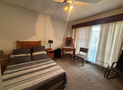 a bedroom with a bed and a desk and a window at Wageney2us in Kempton Park