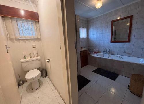 a bathroom with a toilet and a tub and a sink at Wageney2us in Kempton Park
