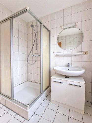 a white bathroom with a shower and a sink at Wolles Sonnenhaus in Wirdum