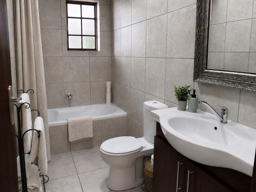 a bathroom with a toilet and a sink and a tub at Alimento Guest House in Upington