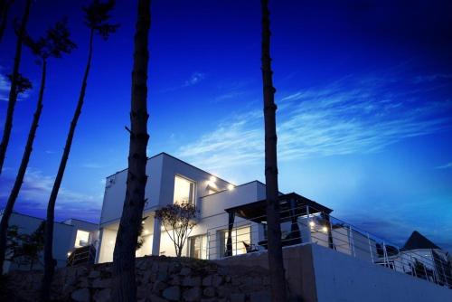 a white house with lights on in the night at The Mare Pool Villa Pension in Taean
