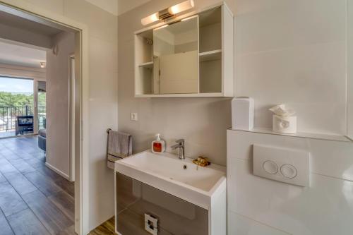 a white bathroom with a sink and a mirror at Apartments Doris in Malinska