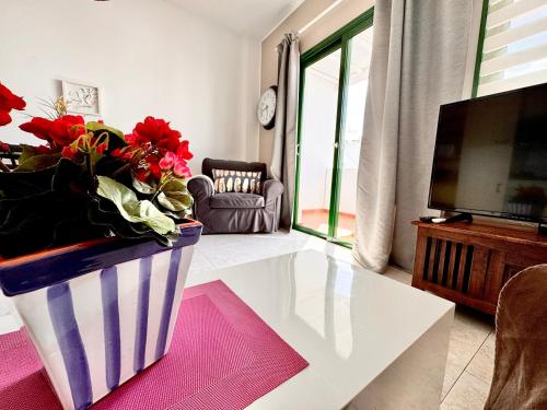 a living room with a vase with red flowers in it at Departamento Corriquia in Playa Blanca