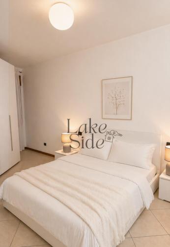 a white bedroom with a large bed with a take side sign at Bijou - Lake side apartments in Sandra