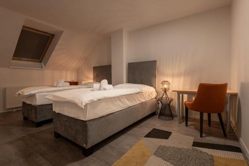 a bedroom with two beds and a table and a chair at Hotel Novy Kastiel - Self check-in in Topoľčany