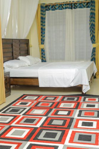 a bedroom with a bed and a rug on the floor at Cozy Retreat in Kampala