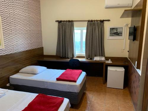 a hotel room with two beds and a desk at Ibitur Hotel in Ibiúna