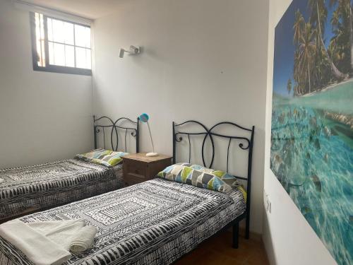 two beds in a room with a painting on the wall at Atlantic Breeze House I Double Rooms at EL CAMPANARIO I 5 minutes from Popcorn Beach in Corralejo