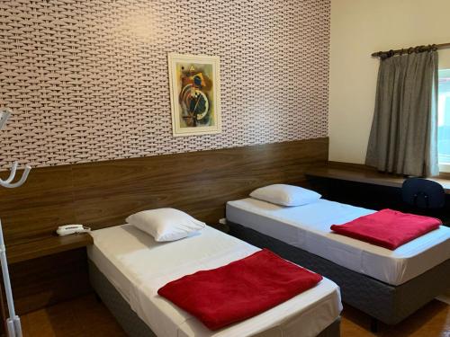 a room with two beds with red sheets at Ibitur Hotel in Ibiúna