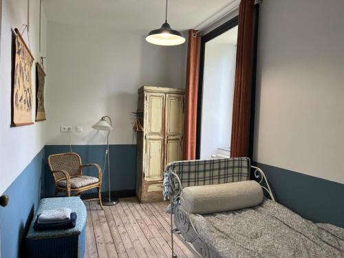 ein Schlafzimmer mit einem Bett, einem Stuhl und einer Lampe in der Unterkunft L'école perdue in Saint-Martin-dʼOllières