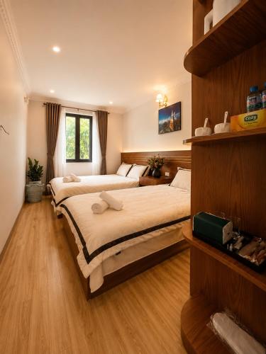 two beds in a bedroom with wooden floors at SaPa PAPA - Architect's Hidden Sanctuary - Only 4 rooms hidden in a secret botanical garden - 3 minutes from Sapa Station - Privacy & Privilege for stylish insiders in Sapa