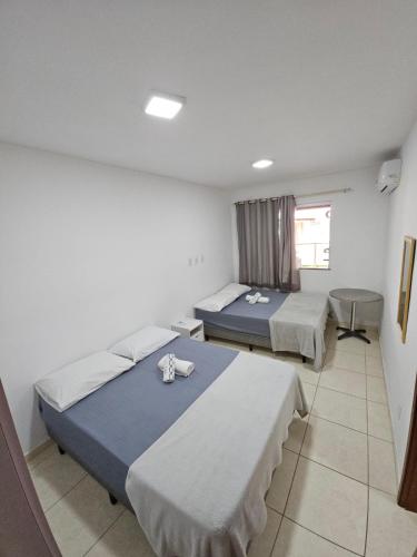 a room with three beds and a window at Pérola Rosa 04 in Ilhéus