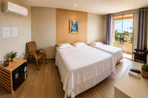 a hotel room with two beds and a window at Pousada Hope Club in Beberibe