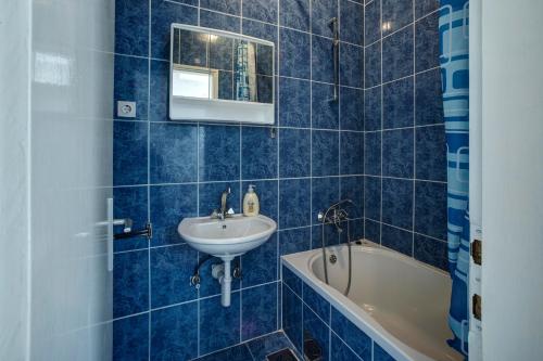 a blue tiled bathroom with a sink and a tub at Apartmani Juricev Vodice in Vodice