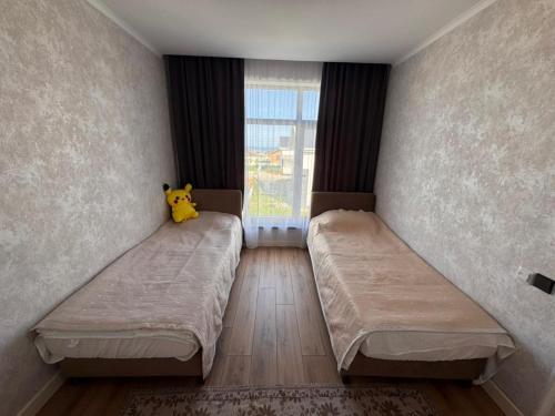 a bedroom with two beds with a stuffed animal on the wall at Karagay resort in Bosteri