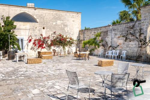 a patio with chairs and tables in front of a wall at Hotiday Torre Guaceto in Brindisi