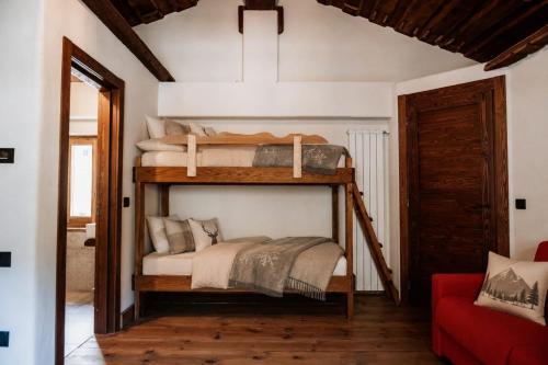 two bunk beds in a room with a red couch at borgo maira village in Prazzo