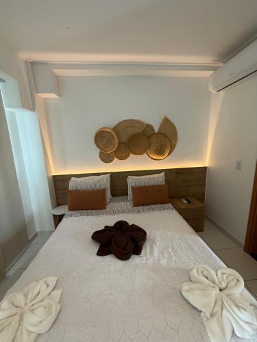 a large white bed with a brown flower on it at Resort Mana Beach Experience By Beachflatsporto in Porto De Galinhas