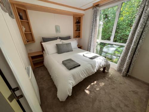 a bedroom with a white bed with a large window at Devon Tor View Country Retreat in Bratton Clovelly