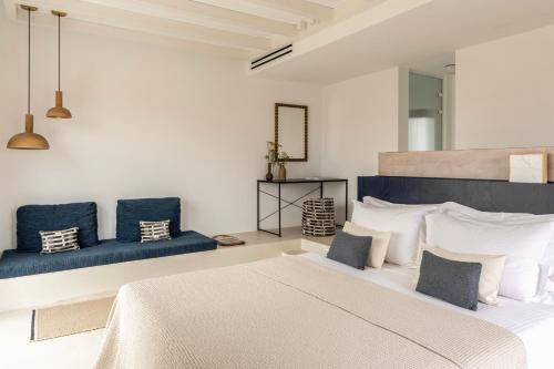 a bedroom with a large bed and blue chairs at ROOTS Nature Living Milos in Adamantas