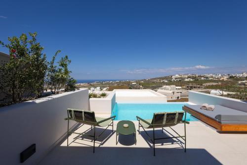a balcony with two chairs and a bed and a pool at Evira Suites in Pyrgos