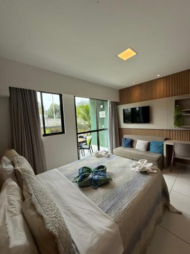 a bedroom with a large bed with two blue shoes on it at Resort Mana Beach Experience By Beachflatsporto in Porto De Galinhas