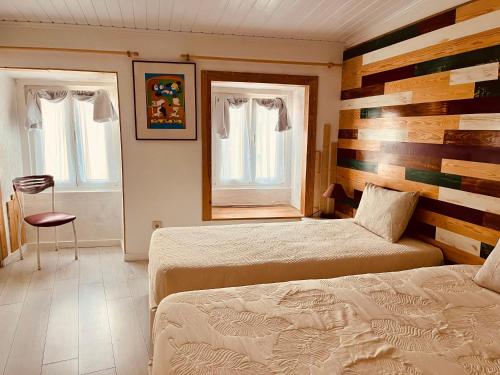 a bedroom with two beds and two windows at Pé do Castelo Casinhas in Tomar