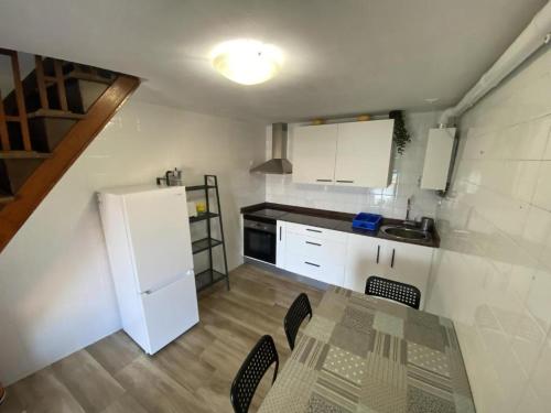 a kitchen with a table and a white refrigerator at La casina de La Fragua in Lastres
