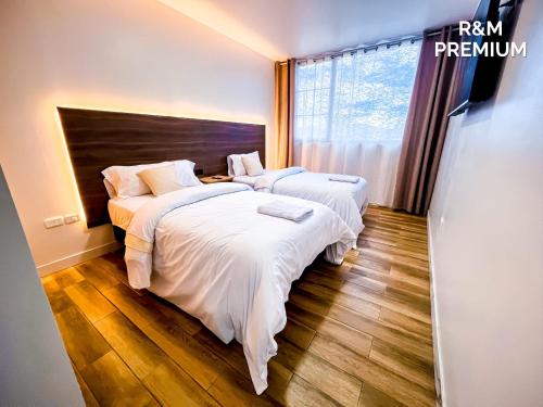 a bedroom with two beds with white sheets and a window at Estancia Exclusiva R&M in Pelileo