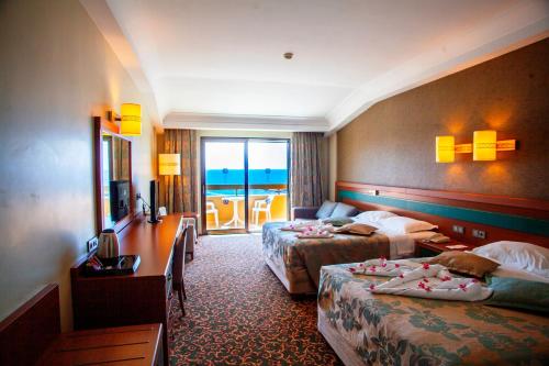 a hotel room with two beds and a balcony at Özkaymak Select Resort Hotel - Ultra All Inclusive in Alanya