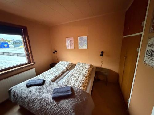 two beds in a small room with a window at Guesthouse Leon - Historic Home Near City Center with Free Parking in Tórshavn
