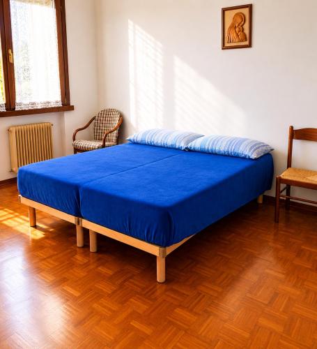 a bed in a room with a blue blanket on it at Charming House Among the Prosecco Hills & Olive Groves in San Pietro di Feletto
