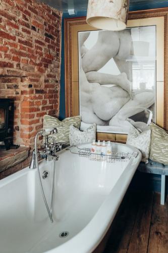 a white bath tub in a room with a painting at The Roebuck Inn in Mobberley