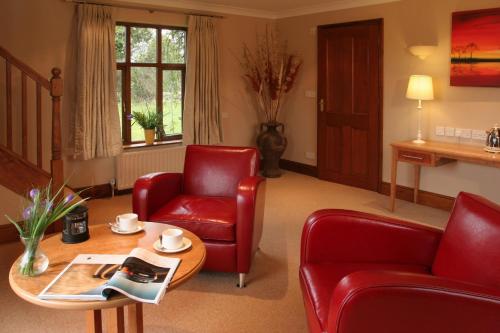 a living room with red chairs and a table at Ivy House Country Hotel in Lowestoft