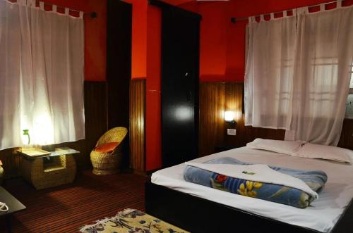 a bedroom with a bed and a chair and curtains at Hotel Kalika Darjeeling in Darjeeling