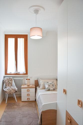 a bedroom with a bed and a chair and a window at 10 min from the lake, Spacious & Modern - Lalaland in Porto Ceresio