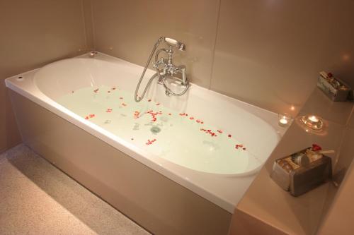 una bañera blanca con aspersiones rojas. en Ivy House Country Hotel, en Lowestoft