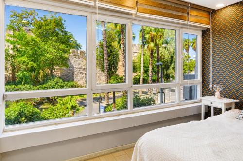 a bedroom with a large window looking out onto a garden at MaxiHomes Hadrian in Antalya