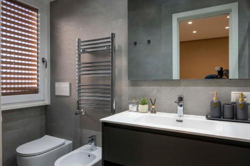 a bathroom with a sink and a toilet and a mirror at Alba Stays in Ladispoli