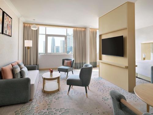 a hotel room with a couch and a tv at Swissôtel Al Murooj Dubai in Dubai