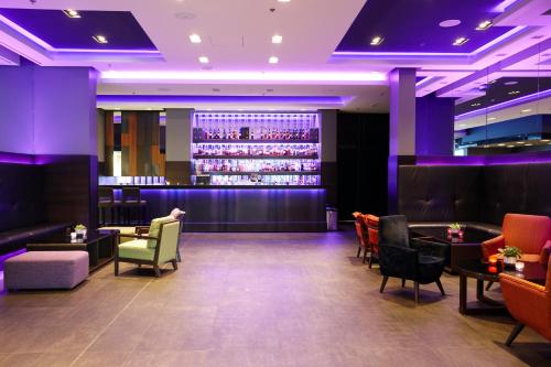 a bar with purple lighting and colorful chairs and tables at Hotel Reykjavík Grand in Reykjavík