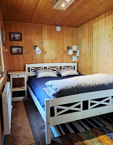a bedroom with a bed in a wooden wall at Peaceful riverside cottage with sauna in Myllykylä