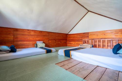 two beds in a room with wooden walls at TB Villa Resort By ARBA in Palayangan