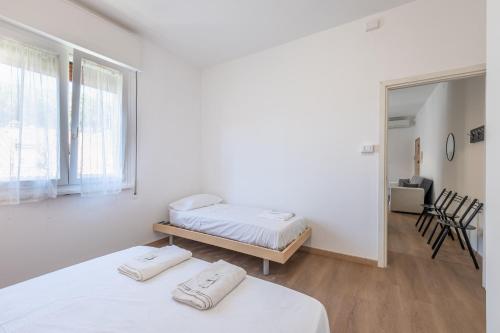 a white room with two beds and a window at Due passi dal mare - Residence Sirena in Punta Marina