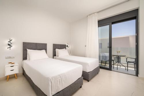 two beds in a hotel room with a balcony at Besa Luxury Villas in Kos