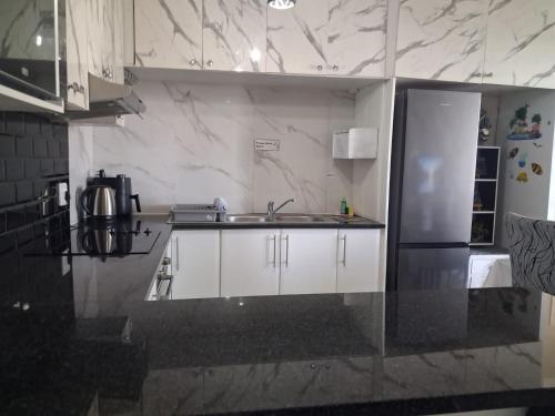 a kitchen with white cabinets and a sink and a refrigerator at Ocean Breeze 12 Boulder Bay in Ballito